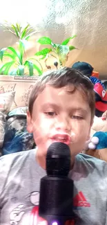 Child singing with a microphone indoors, surrounded by toys.