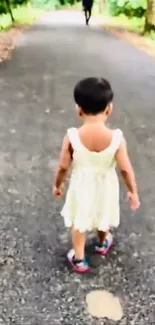 Child in white dress walking on forest path.