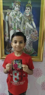 Young child holding a photo in front of framed artwork.