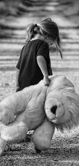 Child holding a large teddy bear on a gravel path, black-and-white image.