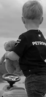 Child holding a teddy bear, monochrome wallpaper.