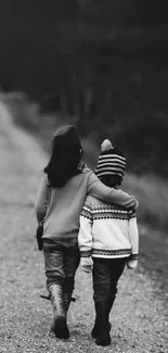 Two children walking on a gravel path in a black and white photo.