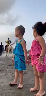 Children holding hands on a beach at sunset.