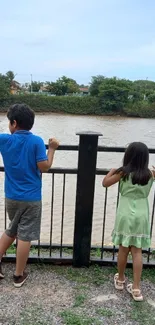 Children by the riverside on a calm day.