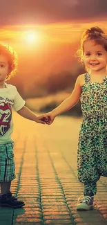 Two children holding hands at sunset, smiling outdoors.