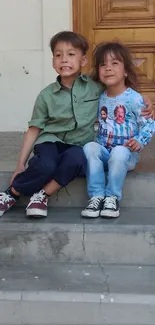 Two children smiling on stone steps in a casual setting.