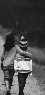 Black and white photo of two children walking on a forest path.