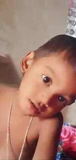 Close-up of a cute child posing indoors with a warm, charming expression.