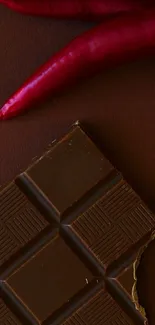 Rich chocolate bar with red chilies on a brown background.