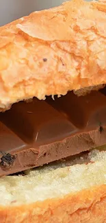 A flaky croissant enveloping a luscious chocolate bar in a close-up view.