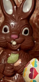 Chocolate Easter bunny with colorful egg in straw bedding.