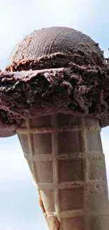 Chocolate ice cream in a cone with sky.