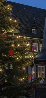 Festive Christmas tree with lights by a charming village house at dusk.