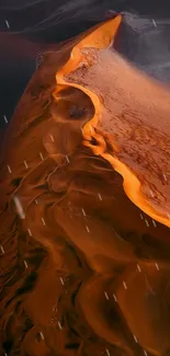 Aerial view of a swirling desert dune with vivid orange tones.