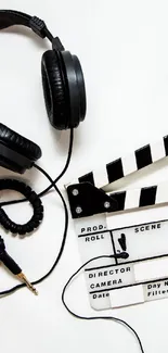 Black headphones and clapperboard on white background.