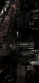 Aerial view of city night streets with glowing lights and bustling traffic.