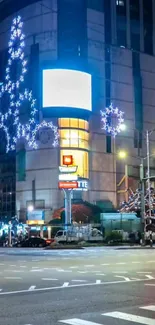 Vibrant city street at night with illuminated signs and blue lights.