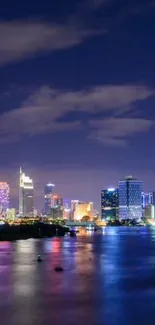 City skyline at night reflected in water.