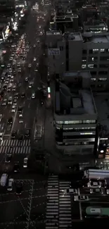 Aerial view of city streets at night with bright lights and active traffic.