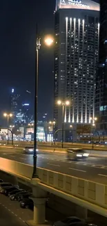 Night view of a city skyscraper and highway with illuminated lights.