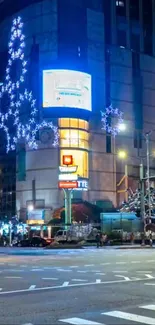 Illuminated city street at night with vibrant building lights.