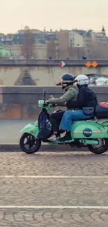 Two people ride a scooter on a city bridge street with a scenic urban view.