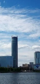 City skyline with tall buildings under a clear blue sky reflected in water.