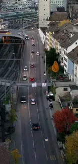 Aerial view of a city street with autumn foliage and buildings.