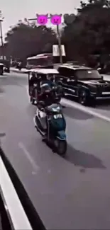 Scooter riding on a busy city street with cars.