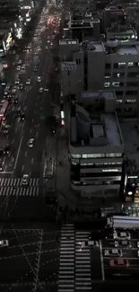 Aerial view of city streets at night with traffic and illuminated buildings.