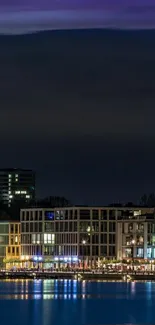 Night cityscape with reflections on water and illuminated buildings.