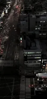 Aerial view of city streets at night with bustling traffic and illuminated buildings.