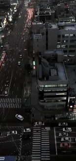 Aerial view of city at night with streets and buildings illuminated.