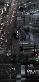 Aerial view of city streets at night with vibrant traffic and illuminated buildings.