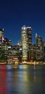 A city skyline at night with reflections on water.