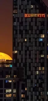 Full moon rising behind city skyscrapers at night.