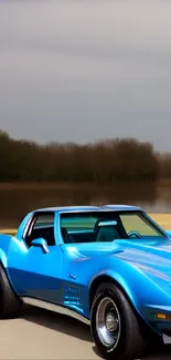 Classic blue car parked by a peaceful lake under a cloudy sky.