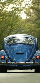 Vintage blue car on a forest road, surrounded by lush green trees.