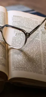 Open book with glasses on a vintage desk as wallpaper.