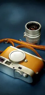 Vintage camera and lens on dark blue background with brown strap.