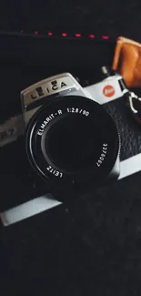 Vintage Leica camera with leather strap on dark background.