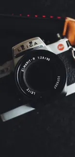 Vintage Leica camera on dark surface, highlighted lens