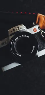 Vintage camera with leather straps on a black backdrop.