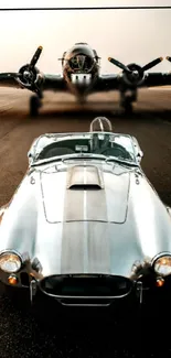 Silver classic car parked in front of vintage airplane on runway.