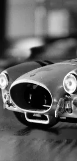 Black and white close-up of a classic car model with headlights.