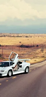 Classic white sports car on desert highway with red cliffs in background.