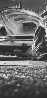 Black and white image of a mechanic working on a classic car in a garage.