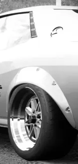 Grayscale wallpaper of a classic car's rear wheel in focus.