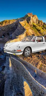 Classic car atop a scenic coastal cliff at sunset.