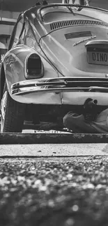 Black and white garage scene with mechanic under vintage car.